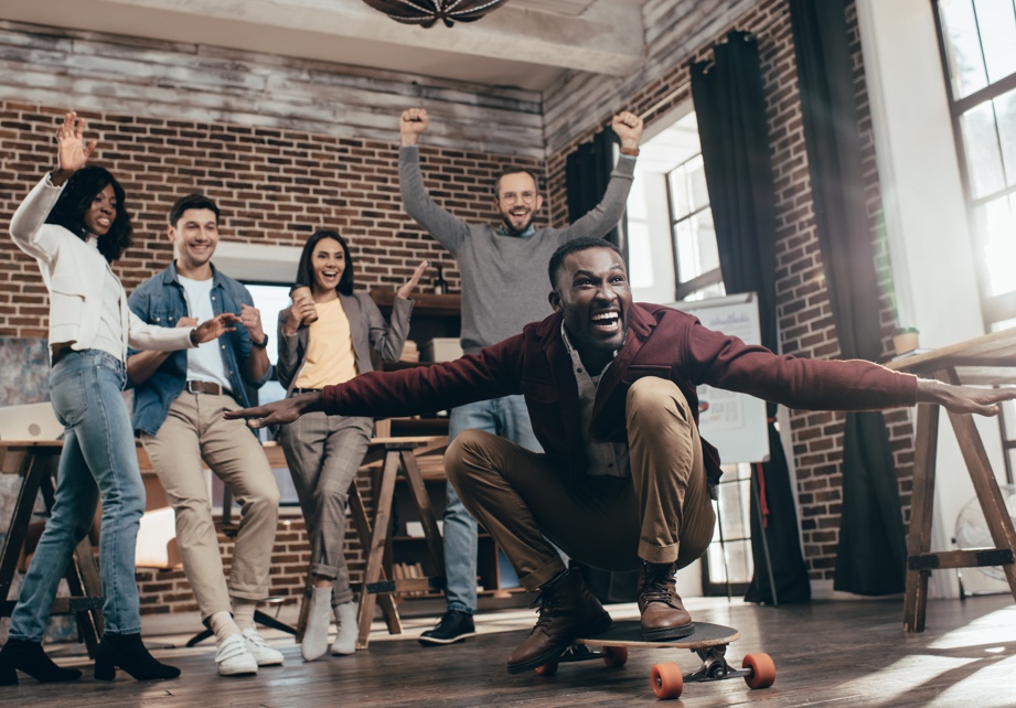 Jubelndes Team mit Mitarbeiter auf einem Skateboard